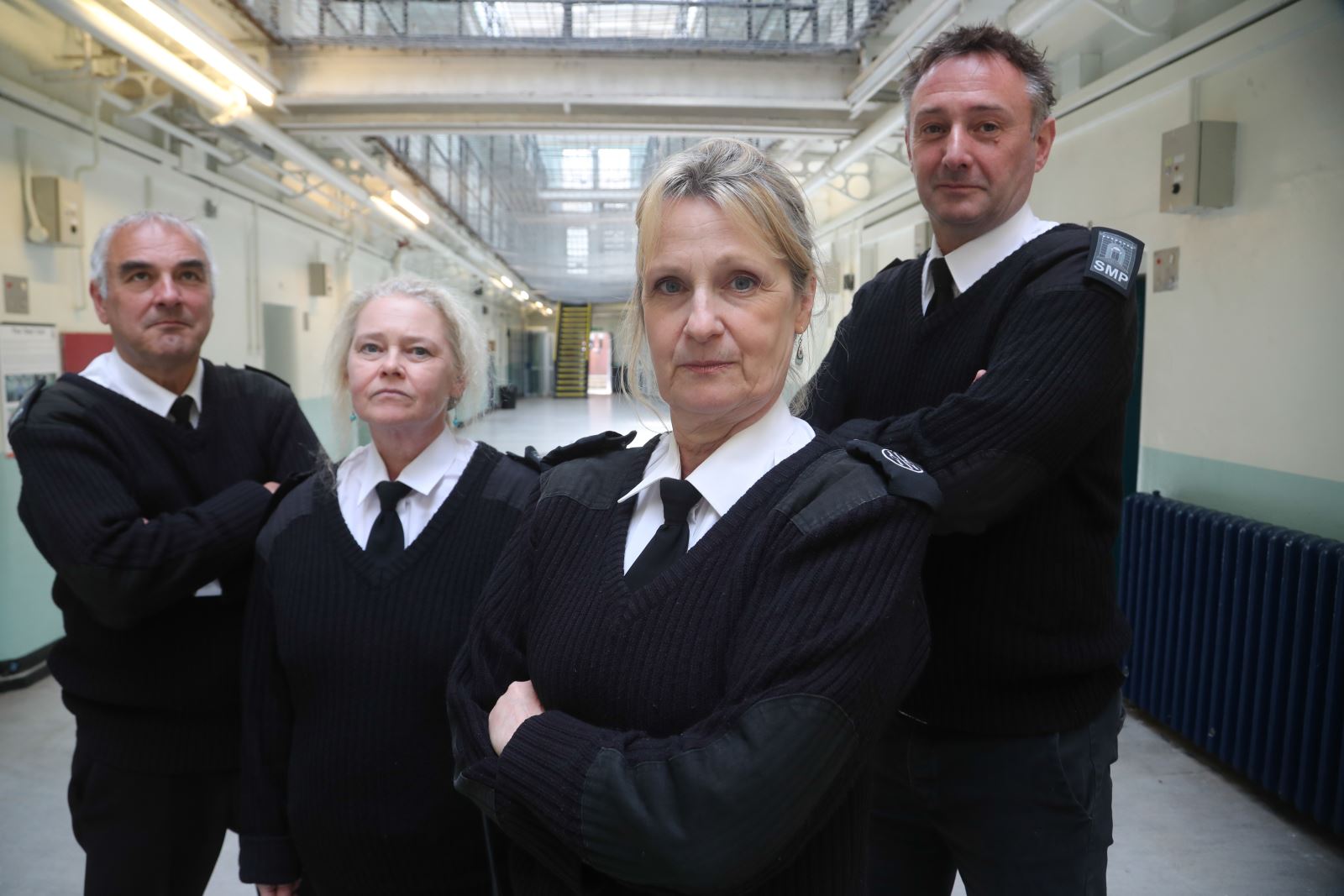 Four prison guards standing on a wing